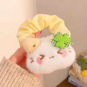 Detail of cute plush cat head with clover charm on a yellow scrunchie hair tie