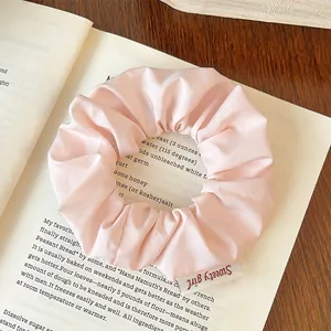 Close-up of pink striped scrunchie with Sweety Girl label on a vintage book background