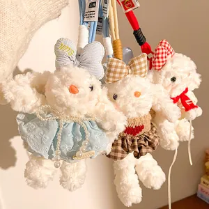 Détail de trois pendentifs lapin en peluche avec des robes en dentelle et des pulls