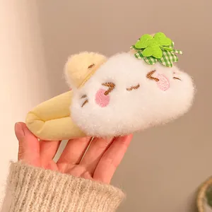 Close-up of cute plush white kitten hair accessory with green clover and pink embroidery