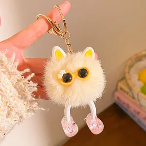 Détail d'un porte-clés peluche monstre jaune avec lunettes et petites chaussures roses