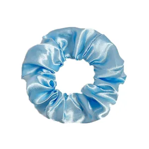 Close-up of a light blue satin scrunchie showing glossy fabric texture and elastic pleats