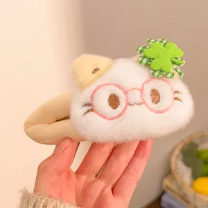 Close-up of plush white cat hair clip with green clover and checkered bow detail