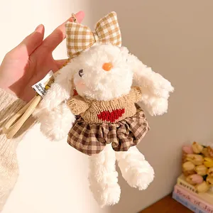 Détail d'un porte-clés lapin en peluche blanc avec jupe à carreaux et pull en tricot