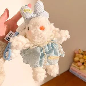 Détail d'un porte-clés lapin en peluche avec nœud rayé bleu et robe en dentelle élégante