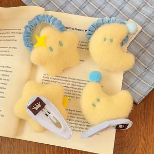 Détail de l'ensemble chouchou étoile et pince lune en peluche sur un fond à carreaux