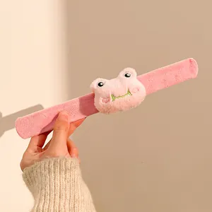 Detail eines rosa Plüsch-Schnapparmbands mit süßer bestickter 3D-Frosch-Applikation