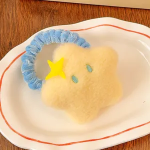 Vue détaillée de l'élastique à cheveux étoile jaune en peluche sur une assiette blanche