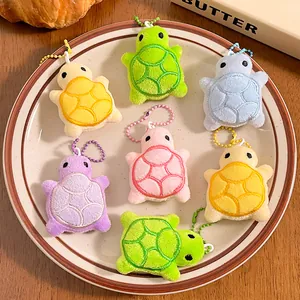 Colorful plush turtle keychains with embroidered details on a white ceramic plate