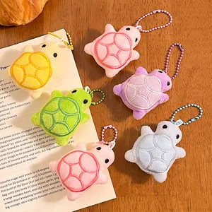 Cute plush turtle keychain charms in six vibrant colors on a rustic wooden background