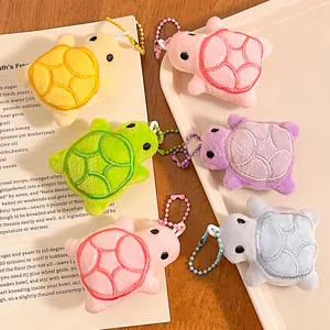 Cute plush turtle keychains in six colors with colorful embroidered shells on a white tray