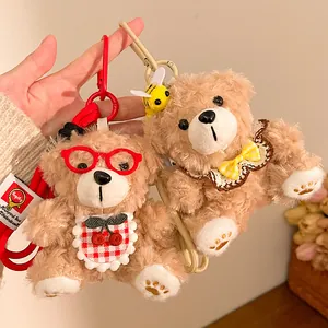 Close-up van schattige pluche beer sleutelhangers met bril en bijendecoratie voor tas