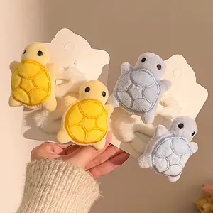 Close-up of cute plush turtle hair clips with embroidery detail on card packaging