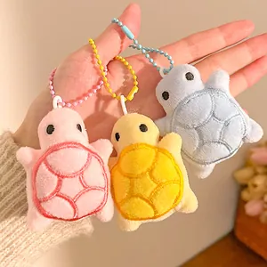 Detailed view of three mini plush turtle keychains in pink, yellow, and blue colors