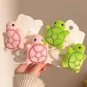 Close-up of cute plush turtle hair clips in pink and green with embroidery details