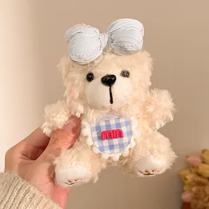 Detail van een crème pluche teddybeer sleutelhanger met blauwe strik en ruitjespatroon