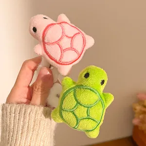 Close-up of cute plush turtle hair clip with detailed embroidery and soft fabric texture