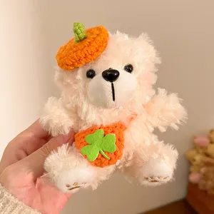 Detail van een crème teddybeer pluche sleutelhanger met oranje muts en klavertasje