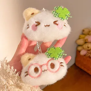 Detail of plush cat keychains with clover decorations and white fluffy texture