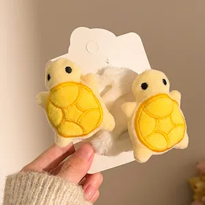 Detail of cute plush yellow turtle hair ties with soft white faux fur on display card