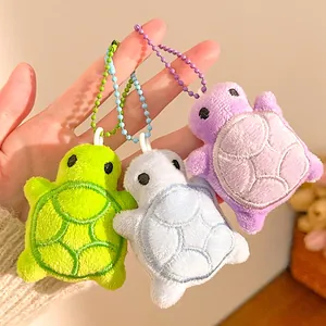 Close-up of soft turtle plush keychain in green, light blue and purple colors