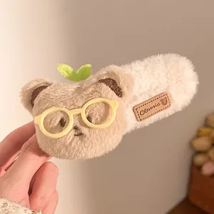 Detailansicht einer Plüschbär-Haarklammer mit kleiner Brille und grünem Sprossen-Detail