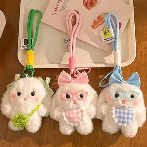 Three cute plush lop-eared bunny keychains with colorful bows and accessories on wooden tray