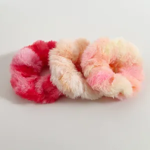 Detalle de tres coleteros de peluche tie-dye coloridos con textura suave y esponjosa