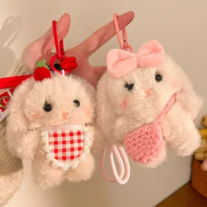 Close-up of cute plush bunny keychains with strawberry and bow details in soft faux fur