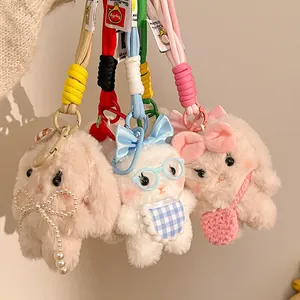 Detail of plush bunny keychains featuring beige, white, and pink characters with accessories