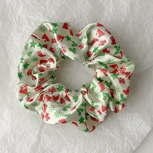 Detailed view of Christmas themed satin scrunchie with festive hat and snowflake patterns