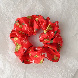Close-up of red Christmas hair scrunchie with silk texture and reindeer print patterns