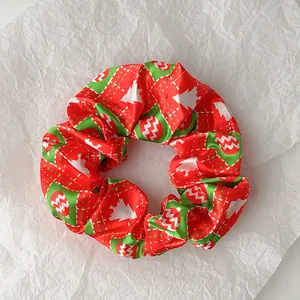 Close-up of red and green Christmas scrunchie with festive tree and ball patterns