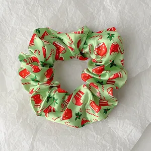 Macro shot of light green satin Christmas scrunchie with festive socks and candy patterns