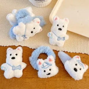 Detail of plush white bear hair clips with blue hats and happy embroidery on wood
