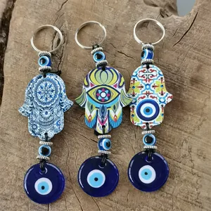 Three Evil Eye Hamsa Hand keychains with colorful mandala patterns on wood surface