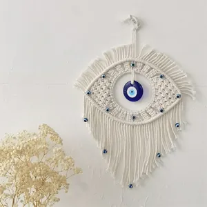 Handmade macrame evil eye wall hanging with white cotton ropes and blue bead accents