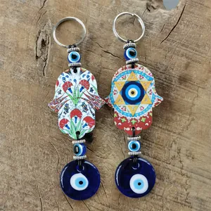 Detailed view of Hamsa hand keychains with evil eye beads on a rustic wooden surface
