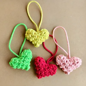 Vue macro détaillée de quatre breloques cœur au crochet faites à la main colorées