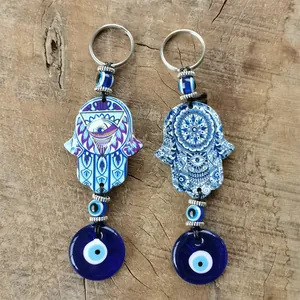 Detailed view of Hamsa Hand and Evil Eye pendants on natural wood background texture