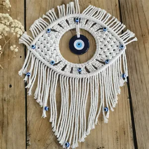 Macro shot of handmade macrame evil eye wall hanging with blue beads and long cotton tassels