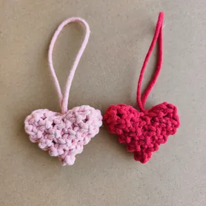 Gros plan sur des pendentifs cœur en crochet faits main en rose et rouge tissés