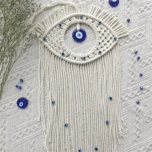 Close-up of handmade bohemian evil eye tapestry featuring blue glass charms and fringe