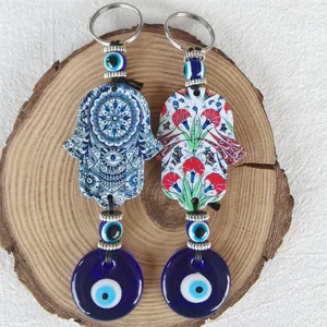 Detail of Hamsa Hand and Evil Eye keychains with mandala patterns on a wooden surface