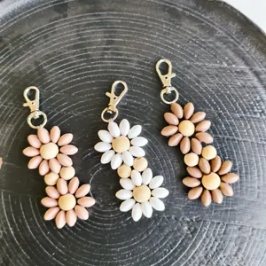 Close-up of daisy-shaped keychains in pink, white, and brown with silver lobster clasps