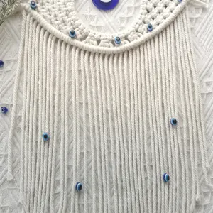Close-up of macrame cotton rope texture and blue evil eye beads on wall hanging