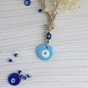 Detail of blue Evil Eye charm with golden beads and woven rope for home or car decor
