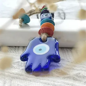 Macro detail of Hamsa Hand and Evil Eye glass pendant with colorful wooden beads