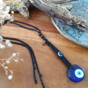 Détail du pendentif œil bleu avec perle en verre et breloque cœur made with love