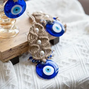 Handmade Evil Eye wall hanging decor with blue glass charm and woven jute leaf accents